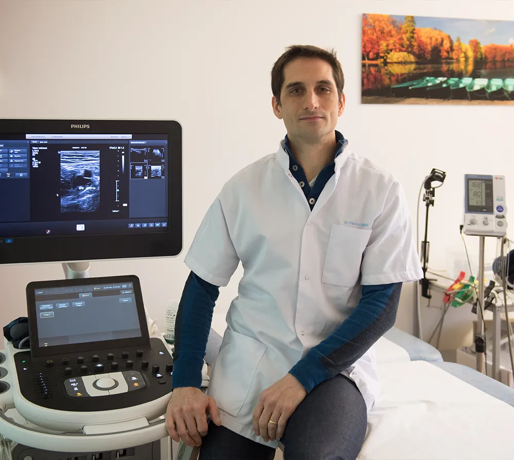 Cardiologue dans son cabinet aux c&ocirc;t&eacute;s d&rsquo;un appareil d&rsquo;&eacute;cho-Doppler cardiovasculaire